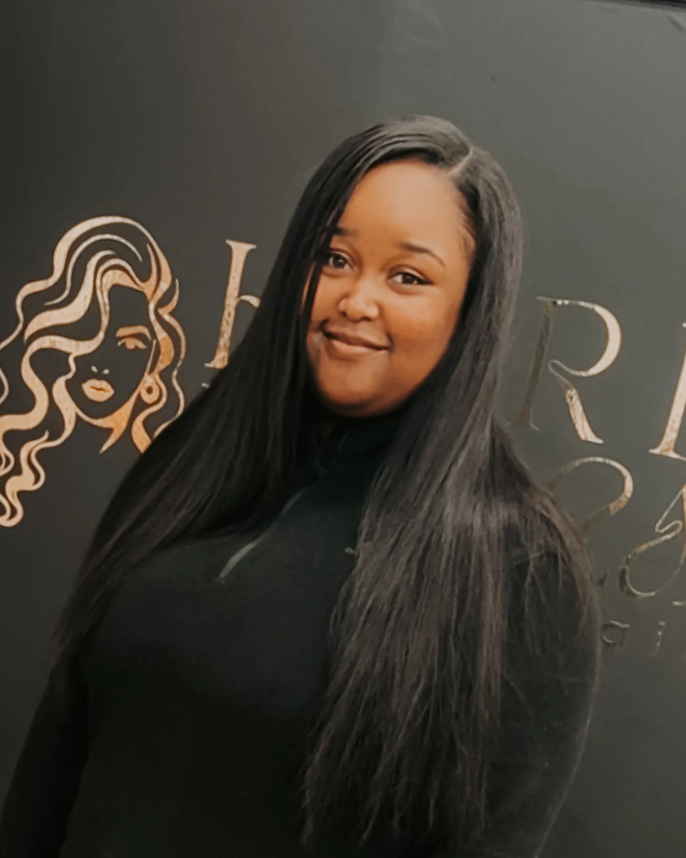 Long sleek straight hairstyle in front of the salon branding